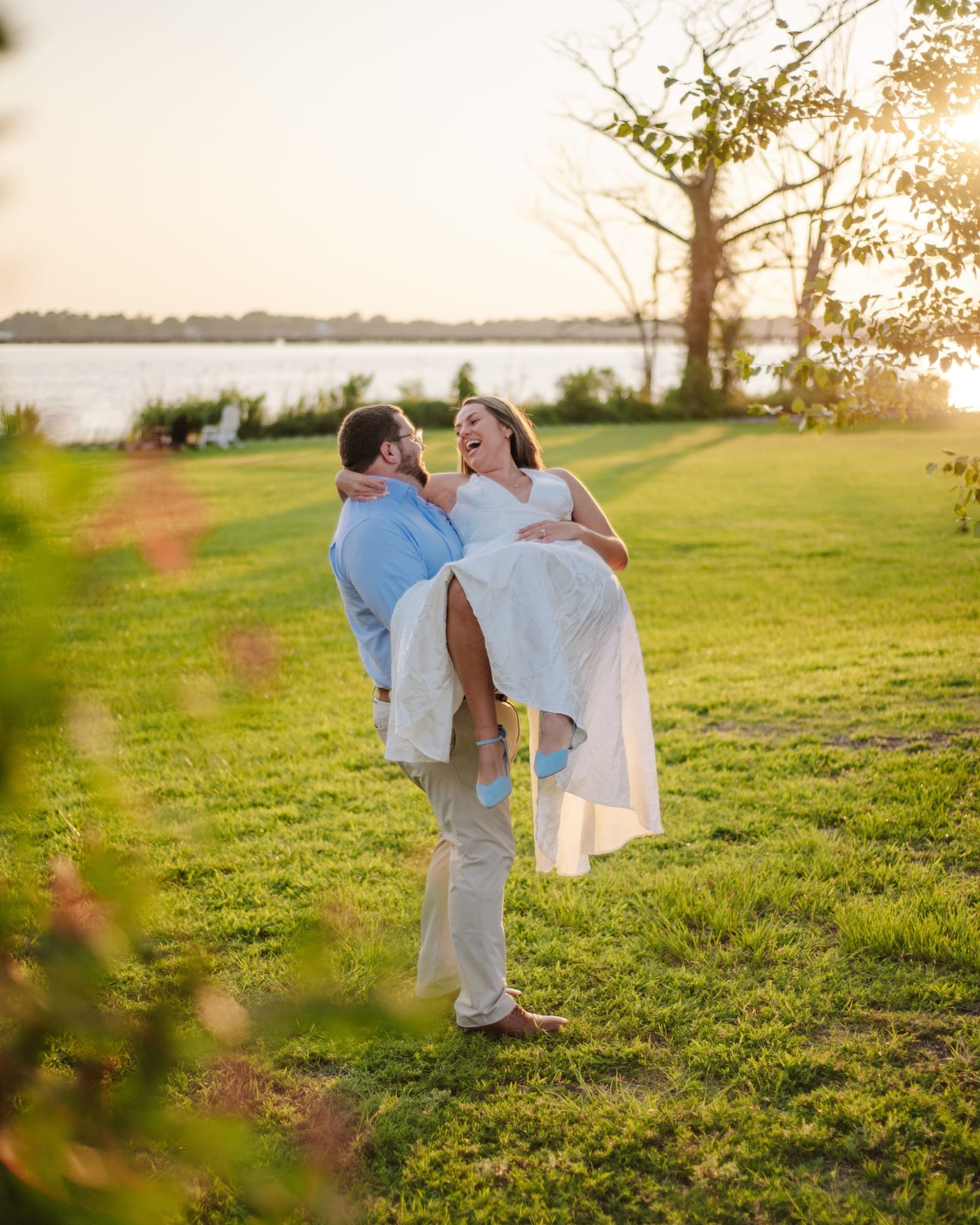 Pierce carrying Katherine across the lawn, both of them laughing, the river behind them.