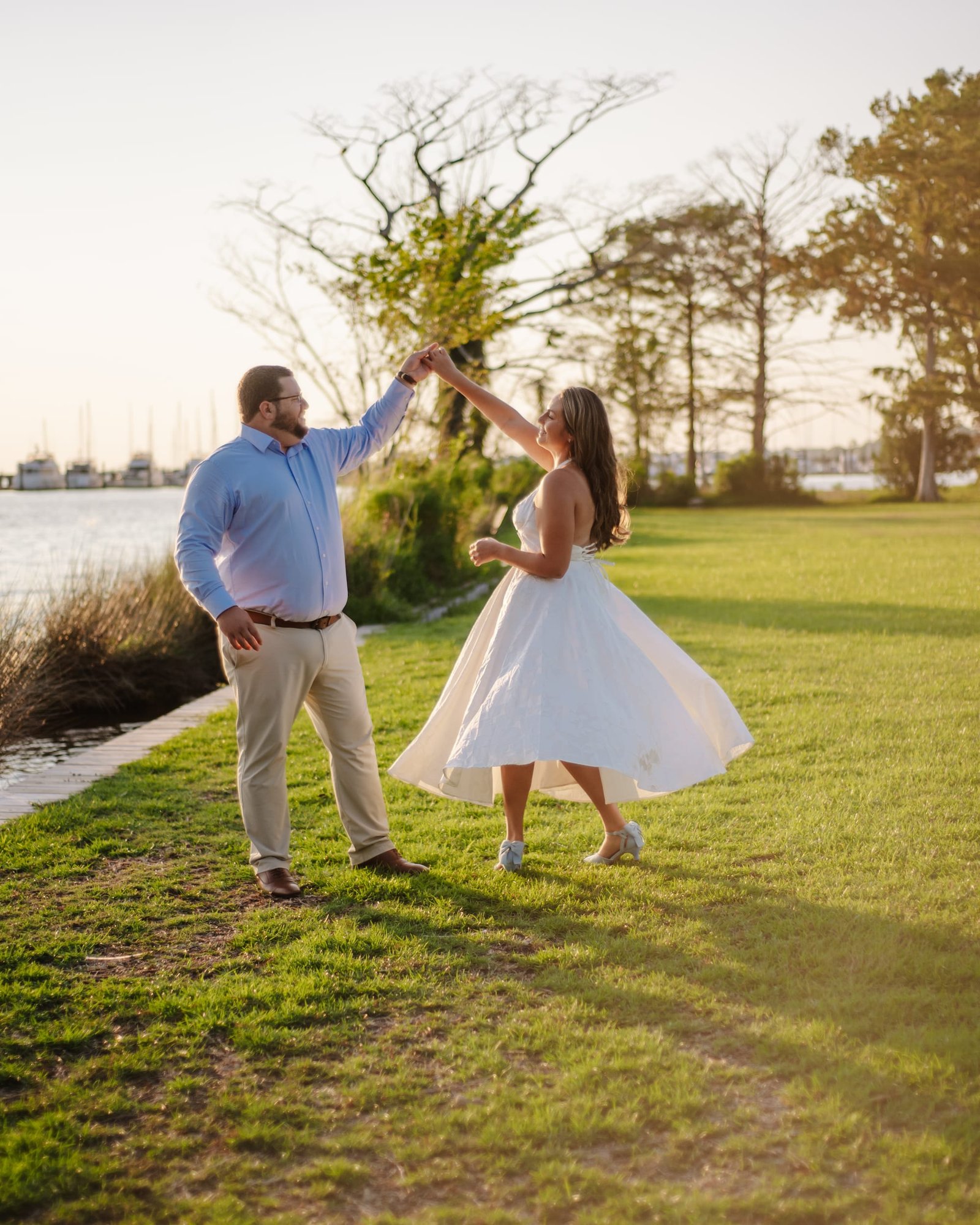 Katherine and Pierce dancing on the lawn by the water at golden hour.